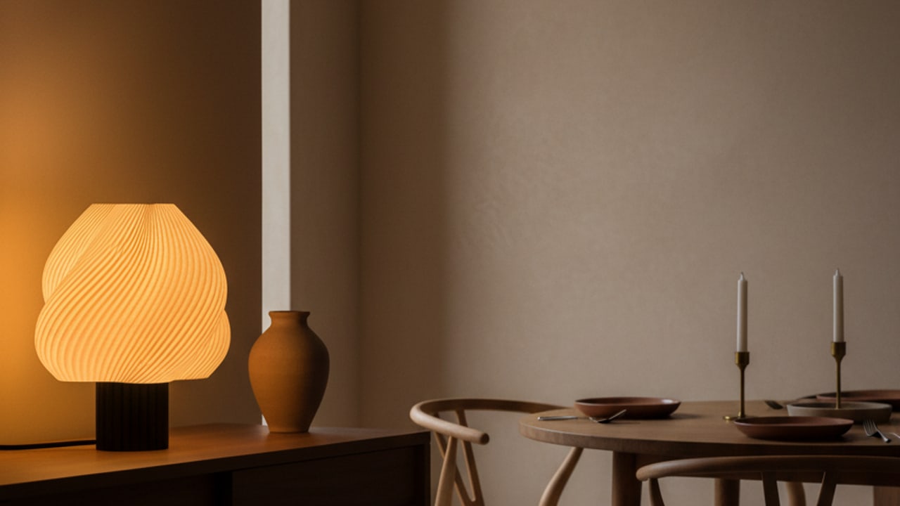 Lumo lamp gloeit warm naast een gedekte eettafel met Wishbone-stoelen
